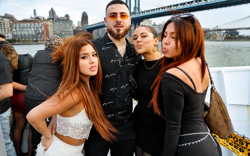Friends posing on a boat near the Brooklyn Bridge